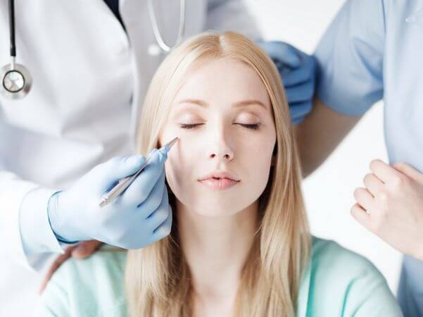 healthcare, medical and plastic surgery concept - plastic surgeon and nurse with patient in hospital